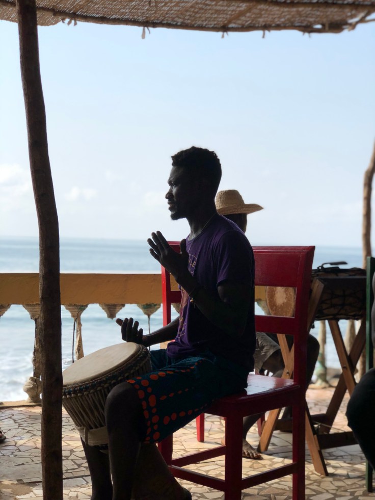 silhouette photo of Namory with a djembe and ocean in background